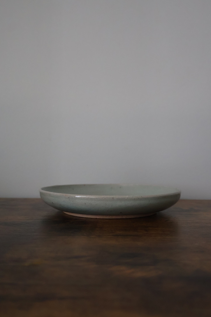 Low celadon ceramic dish on a dark wooden surface