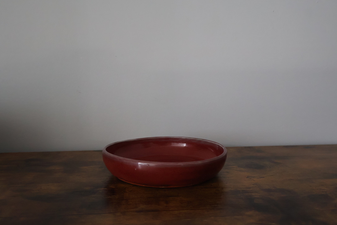 Shallow oxblood red glazed ceramic dish