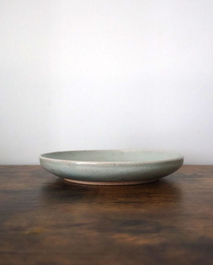 Low celadon ceramic dish on a dark wooden surface